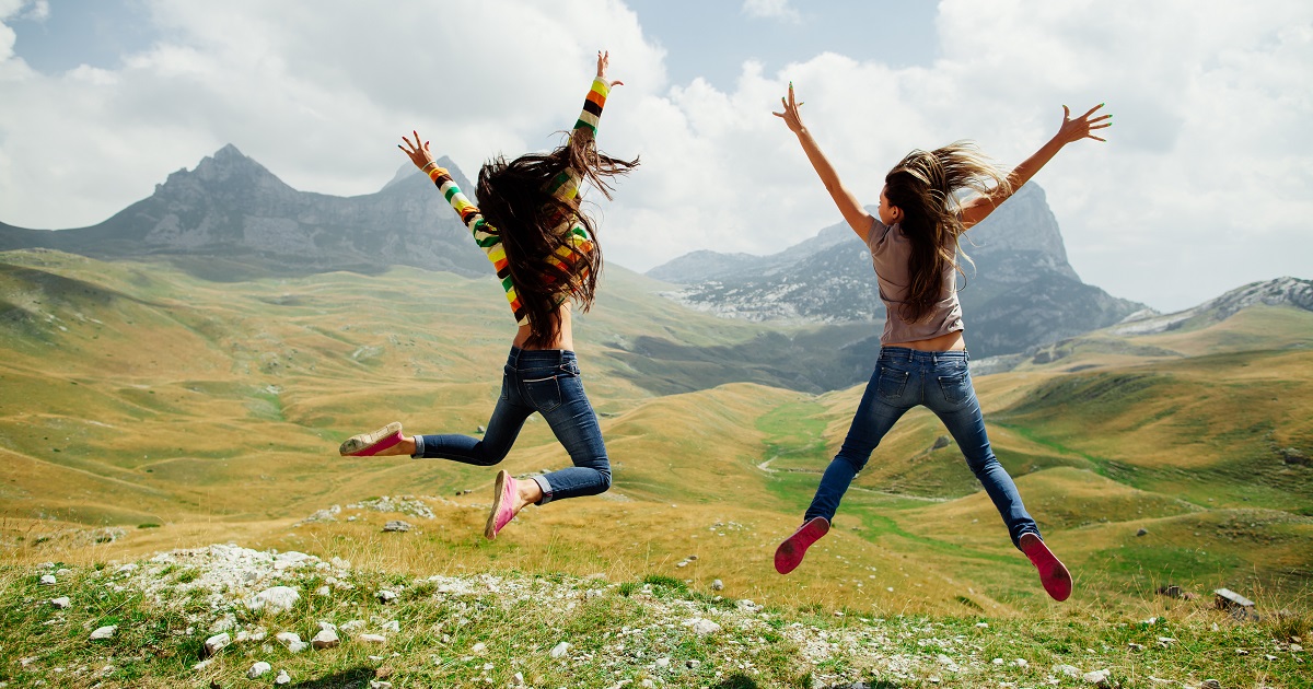 two girls happy jump in mountains with exciting view